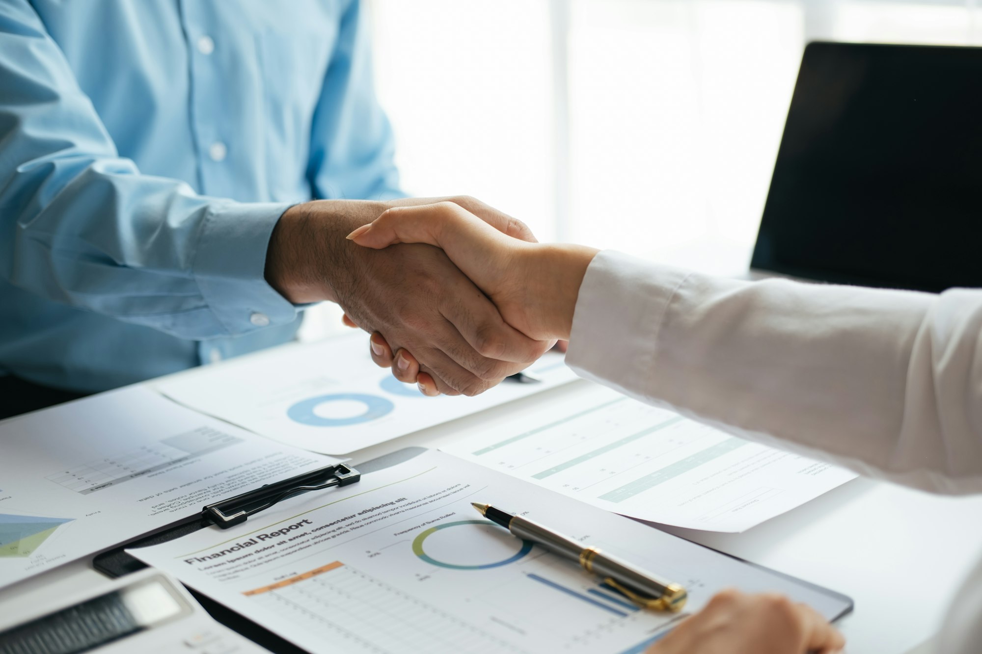 Close up view of business people making a handshake as successful negotiation ending.